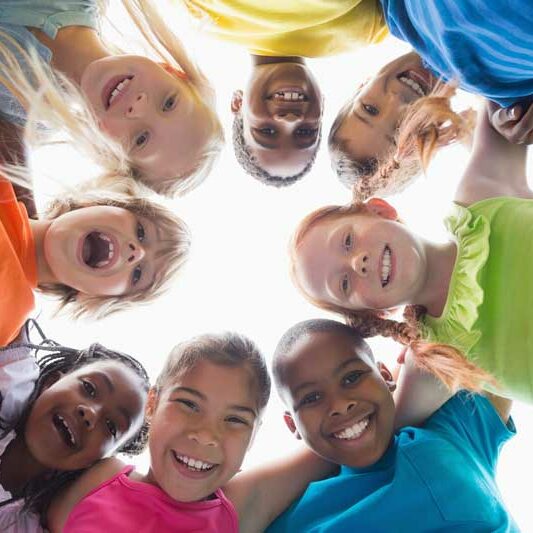 Kids smiling in a circle at summer camp 800x533